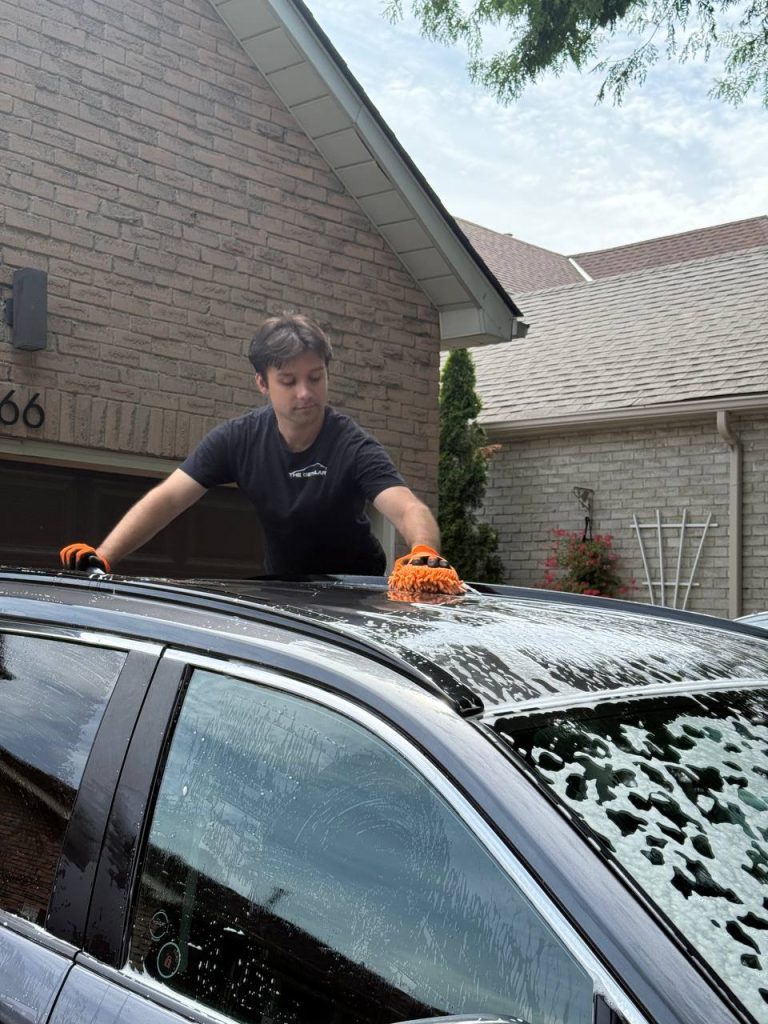 Car detailer washes car roof with a microfiber car mitt in Erin.